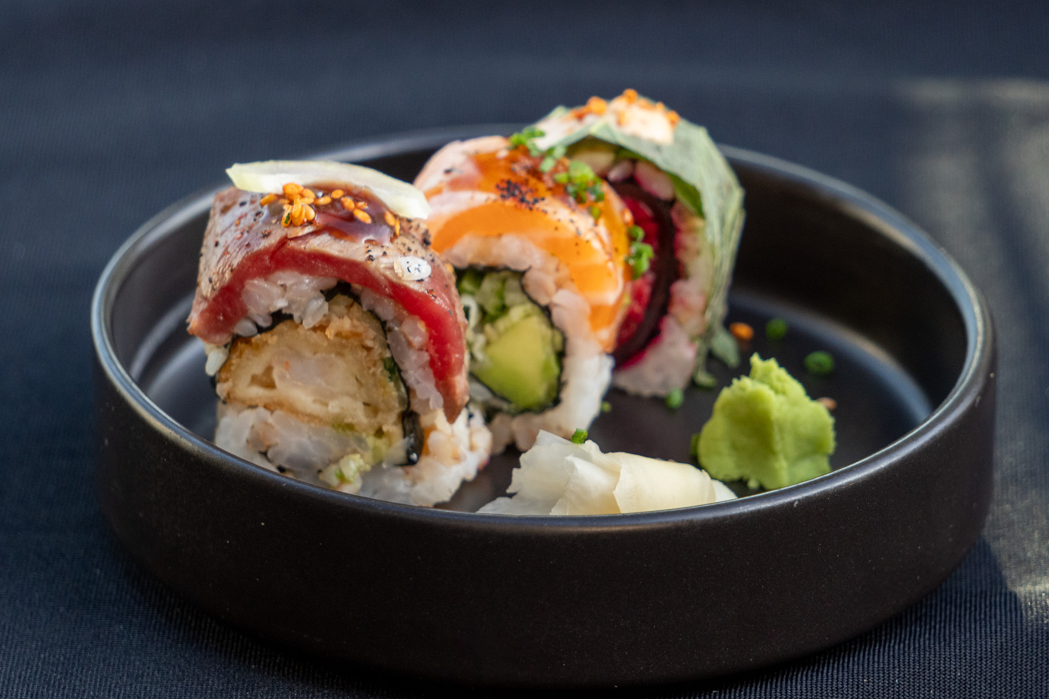 Nahaufnahme von kunstvoll angerichtetem Sushi mit frischem Fisch, Avocado und Reis, garniert mit Sesam und Kräutern, elegantes Fingerfood für das Catering
