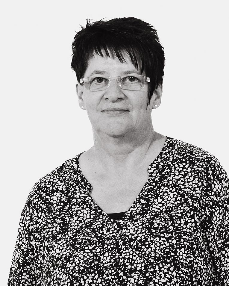 Schwarz-weiß Porträt einer freundlichen Frau mit kurzen dunklen Haaren, Brille und gemustertem Oberteil, Teammitglied des Catering-Unternehmens