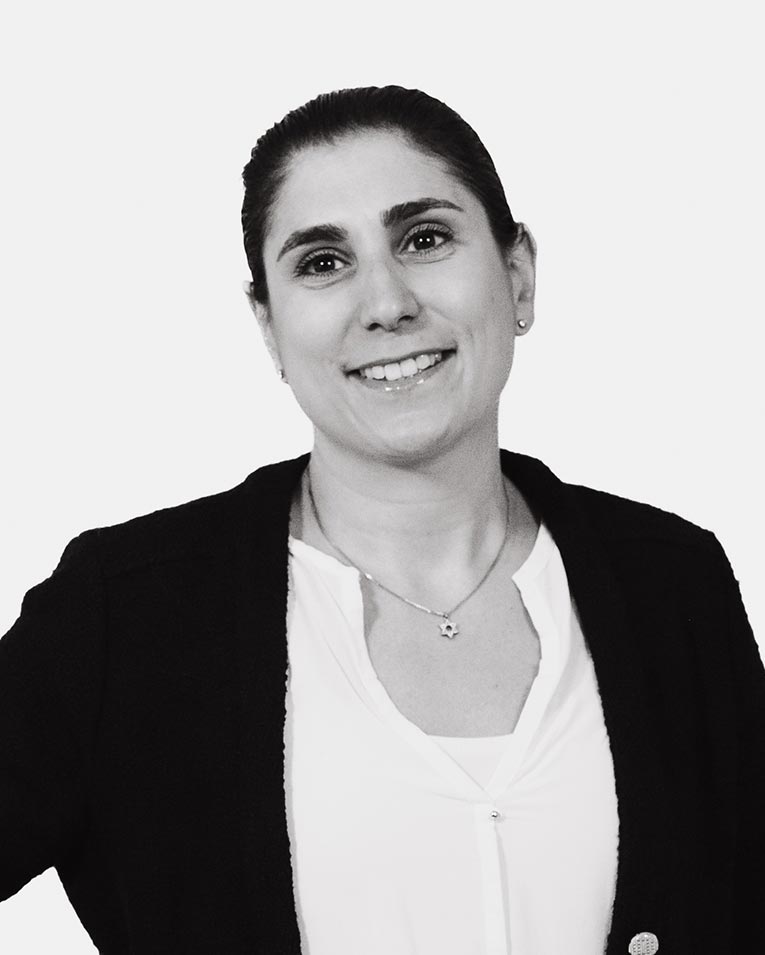 Schwarz-weiß Porträt einer lächelnden Frau mit dunklen zurückgebundenen Haaren, im Blazer und weißer Bluse, Teammitglied des Catering-Unternehmens