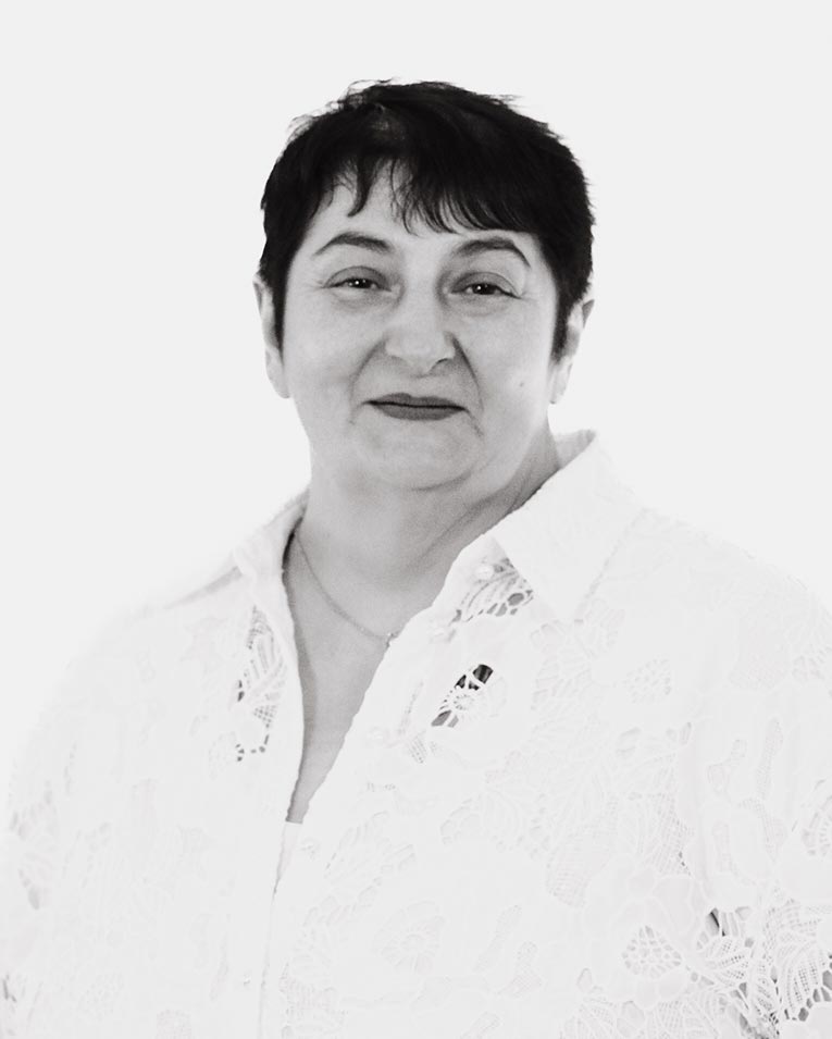 Schwarz-weiß Porträt einer freundlichen Frau mit kurzen dunklen Haaren und weißer Spitzenbluse, Teammitglied des Catering-Unternehmens