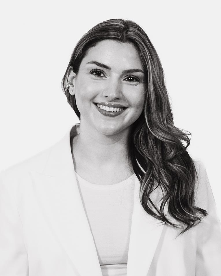 Schwarz-weiß Porträt einer lächelnden Frau im hellen Blazer, Teammitglied des Catering-Unternehmens