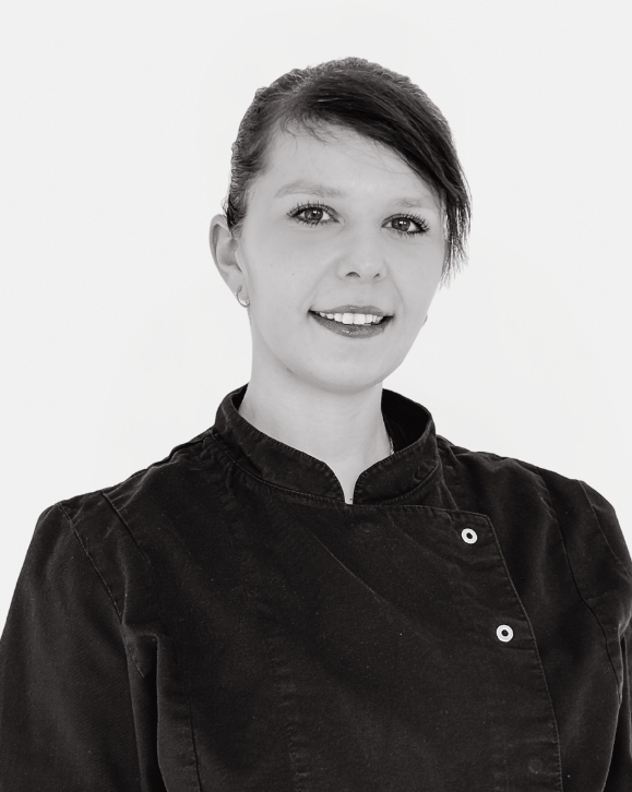 Lächelnde Mitarbeiterin im schwarzen Catering Service Outfit vor hellem Hintergrund in Frankfurt