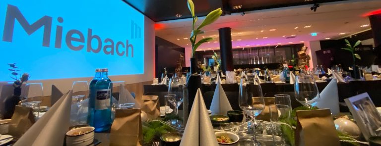 Festlich gedeckte Tische beim Corporate Event Frankfurt mit Miebach-Branding, eleganten Gläsern und Selters-Wasser.