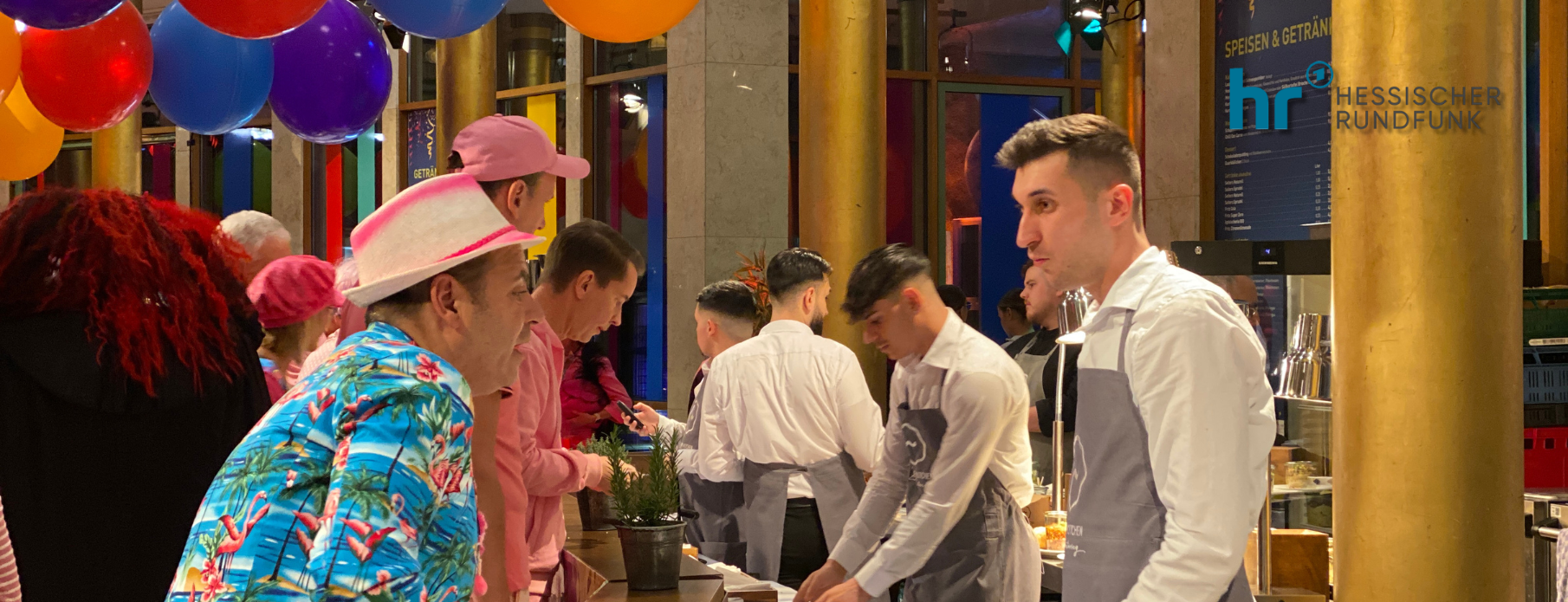 Catering Frankfurt: Servicepersonal bedient kostümierte Gäste an einem Buffet mit bunten Luftballons beim Hessischen Rundfunk-Event.