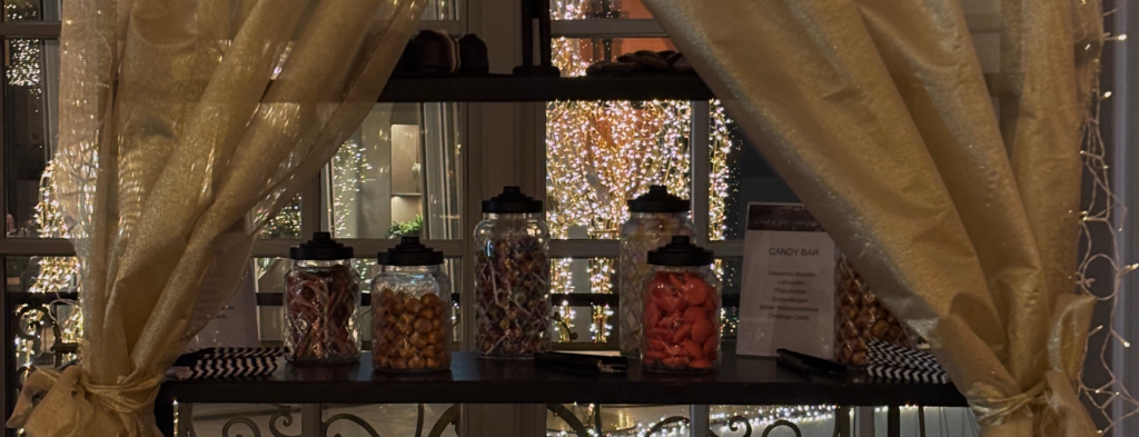 Candy Bar mit gefüllten Glasgläsern beim Catering Frankfurt Event, dekoriert mit Lichterketten und eleganten Vorhängen.