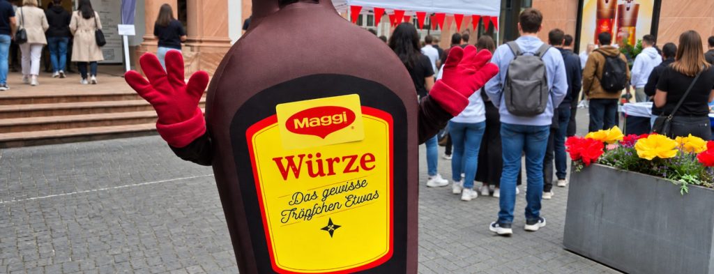 Maggi Würze Maskottchen beim Corporate Event Frankfurt vor einer Menschenmenge auf einem Stadtplatz.
