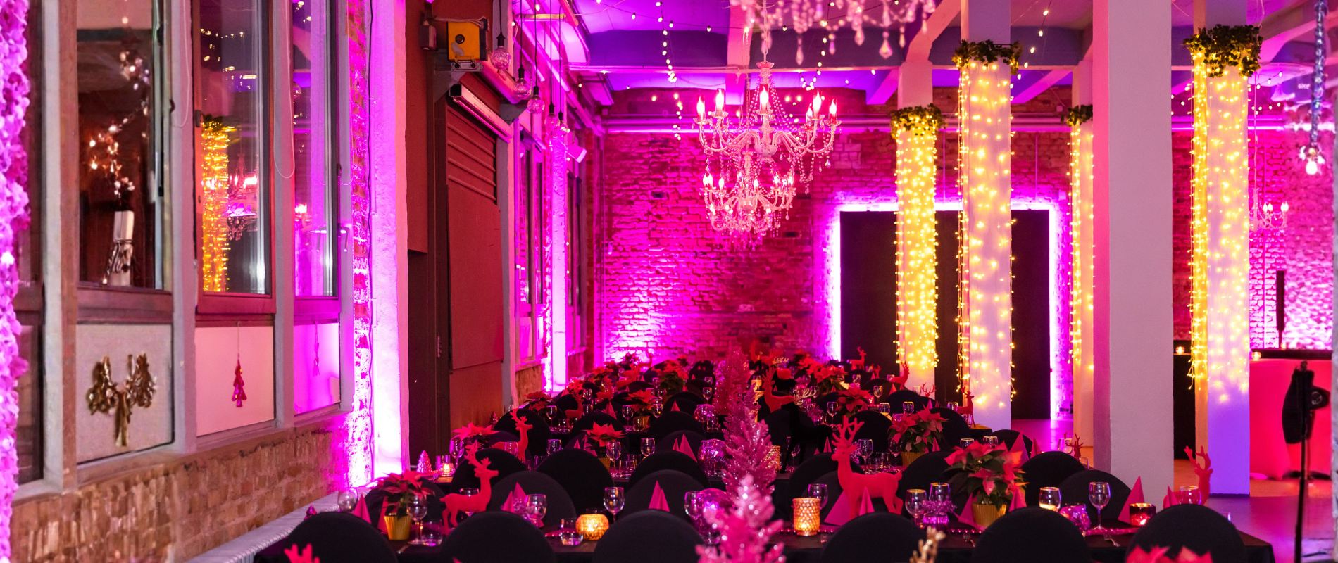 Festlich dekorierter Veranstaltungssaal für ein Corporate Event Frankfurt mit pink-magenta Lichtinstallationen, beleuchteten Säulen und weihnachtlich gedeckten Tischen.