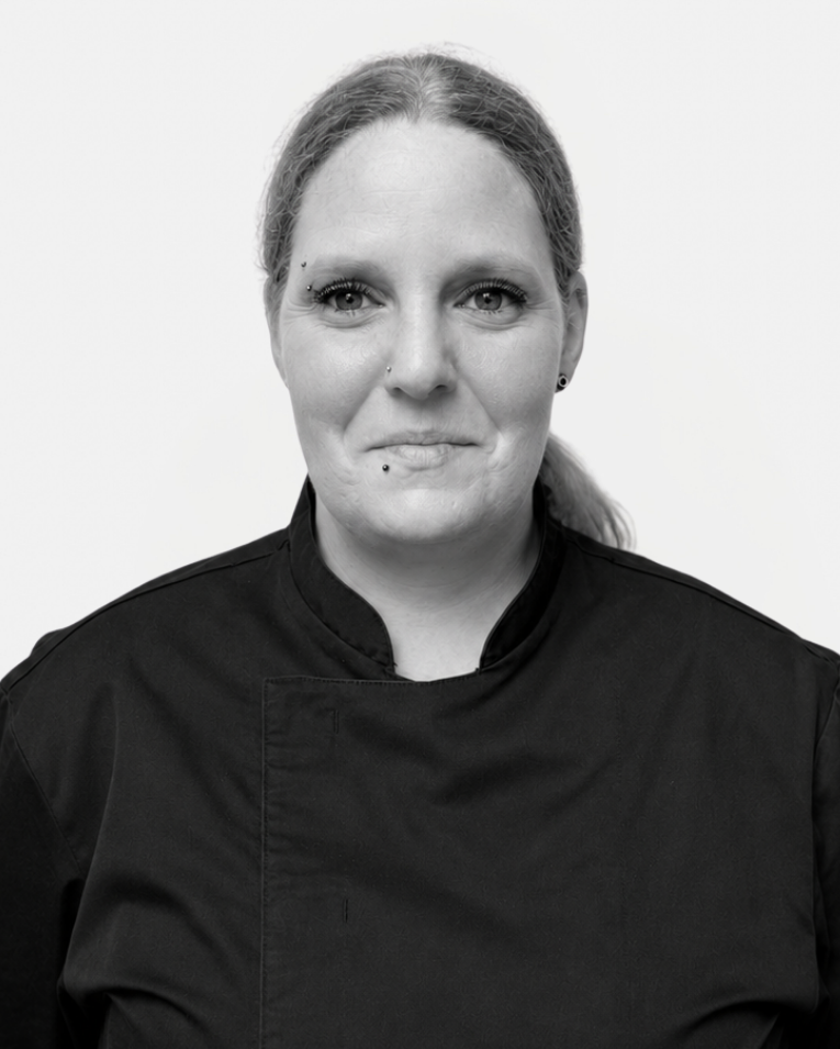 Köchin im schwarzen Kochkittel für Catering Frankfurt, Porträtfoto vor hellem Hintergrund.
