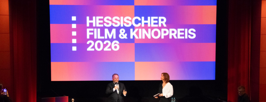 Verleihung des Hessischen Film & Kinopreis 2026 – Corporate Event Frankfurt mit zwei Moderatoren auf der Bühne vor großer Leinwand.